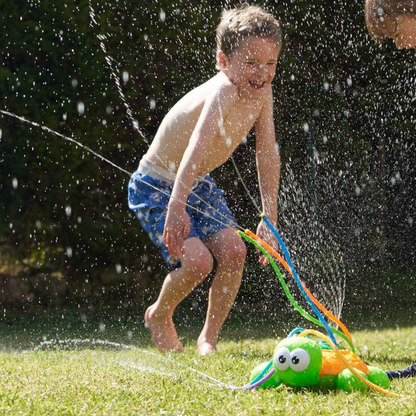 Happy children running through a gentle sprinkler, enjoying outdoor water play in a green backyard on a warm day.