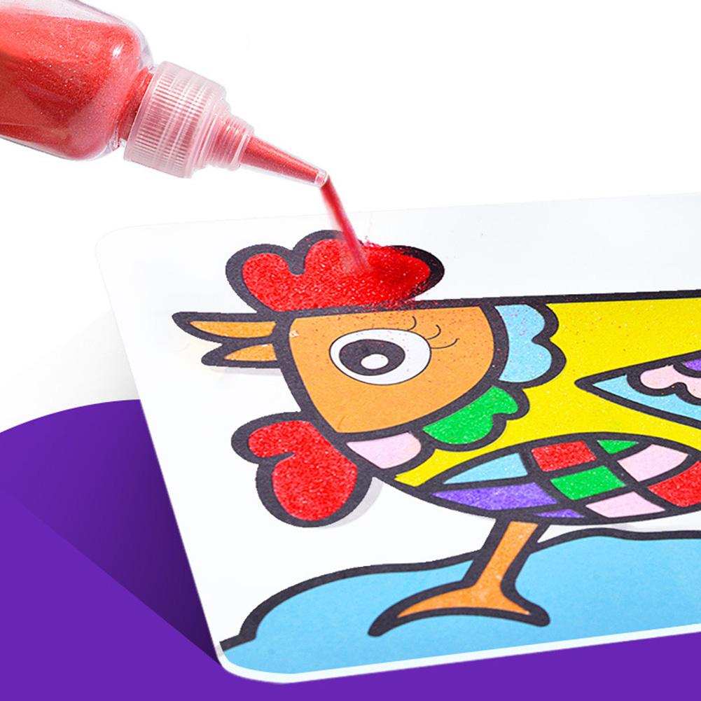 Close-up of a hand pouring brightly colored sand onto a sticky template from a painting kit