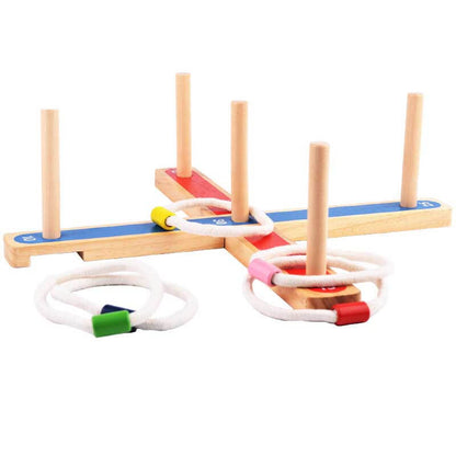 Close-up of child's hand throwing a rope ring onto a wooden peg in an outdoor quoits game
