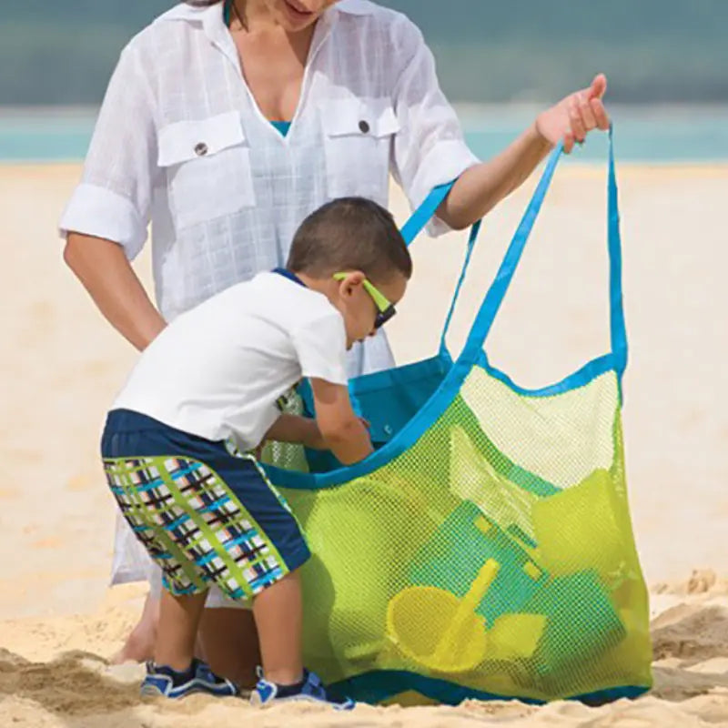 Child reaching into a mesh beach bag to grab a sand toy