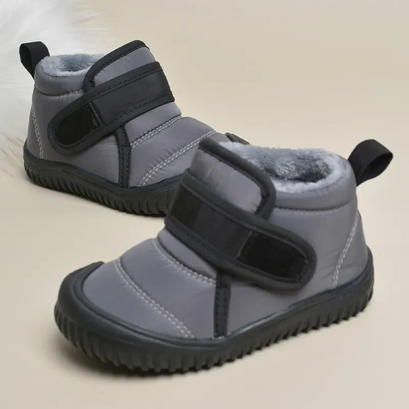 Product shot of kids' warm anti-slip winter snow boots in a snowy environment.