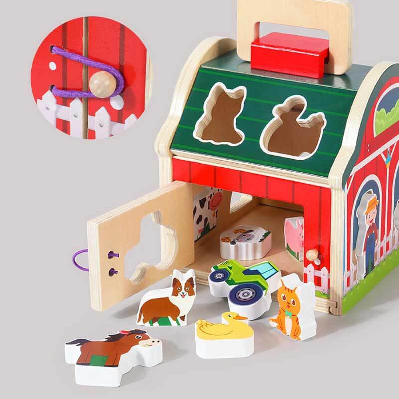 Child's hand placing a wooden animal into the farm sorting barn, developing motor skills