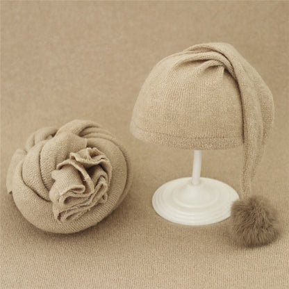 Beige knitted baby swaddle wrap and matching hat with fur pom for infant photoshoot.