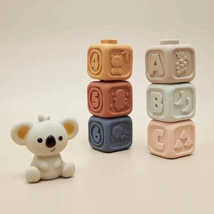 Hand holding a Koala Cubes silicone teether, highlighting its textures for infant relief