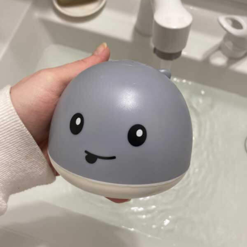 Light-up whale bath toy for toddlers with water spray feature, perfect for sensory water play.