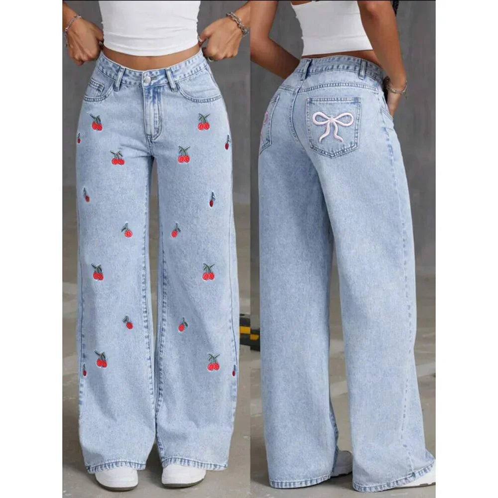 Stylish women's high-waisted wide-leg jeans in light wash denim, adorned with vibrant cherry embroidery; summer ready.
