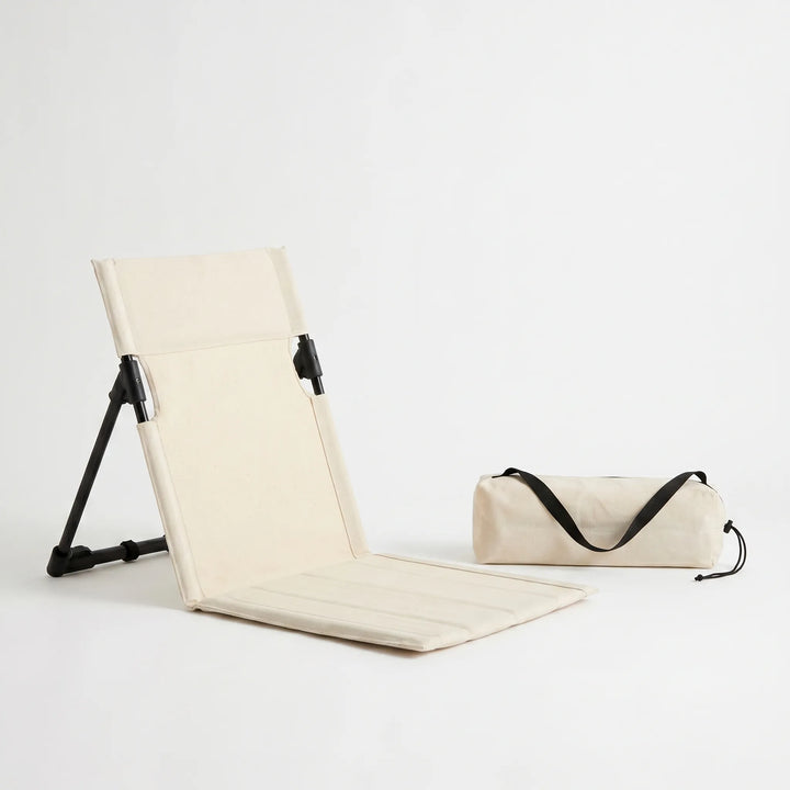 Low profile ground seat with adjustable backrest, providing comfortable support for outdoor activities like fishing.