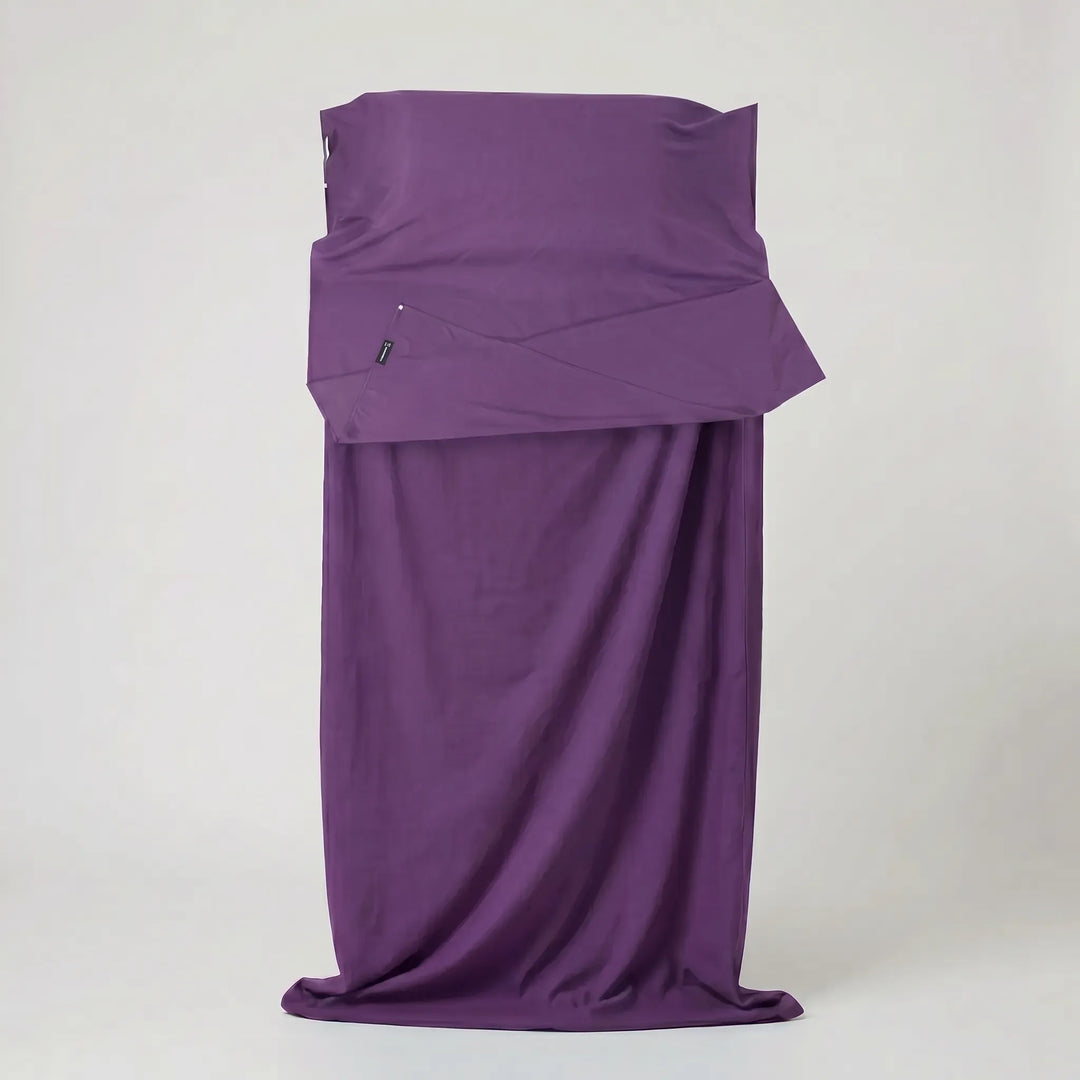 Unisex travel sleeping bag liner unrolled inside a tent, providing lightweight hygiene for camping and hostel trips.