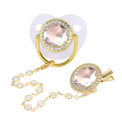 Detailed shot of shiny rhinestone baby pacifier & secure gold clip, newborn essential