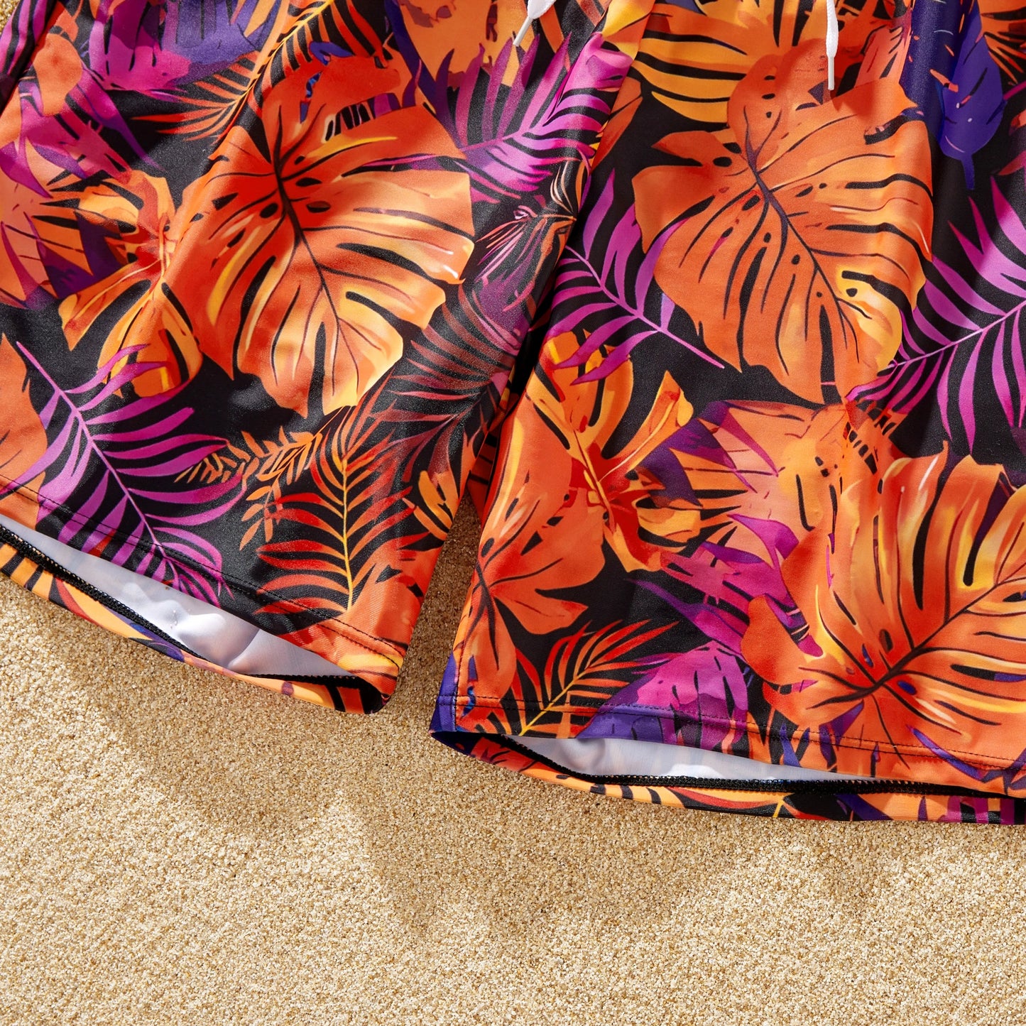 Man in floral drawstring swim trunks playing by the ocean. Summer beachwear.
