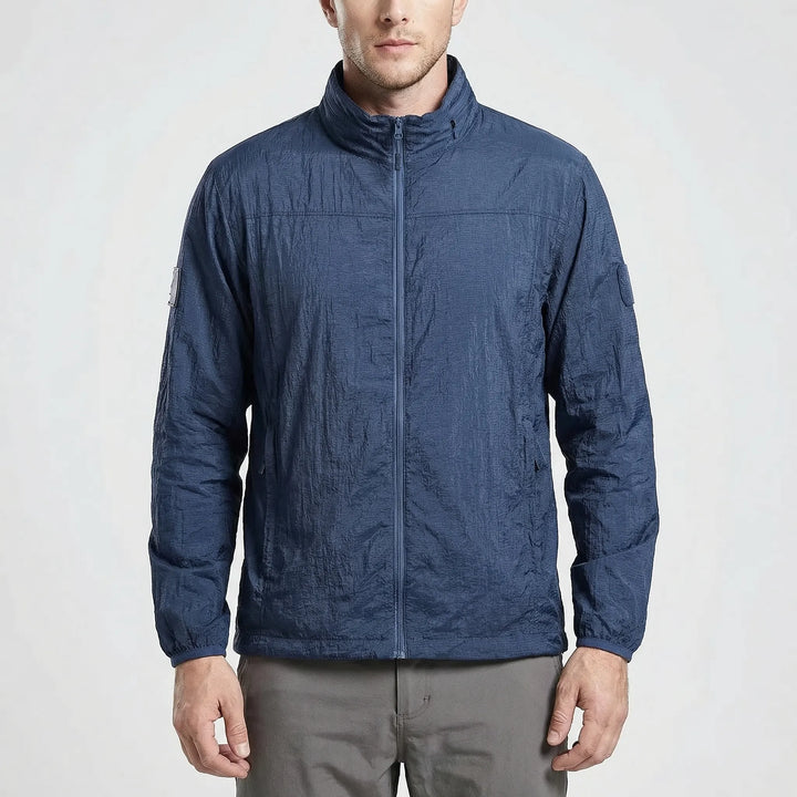Man wearing lightweight tactical hooded windbreaker jacket outdoors, perfect for hiking and travel adventures.