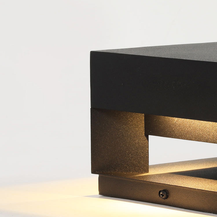 Modern square outdoor wall light mounted on a patio wall, providing warm ambient lighting for evening gatherings.