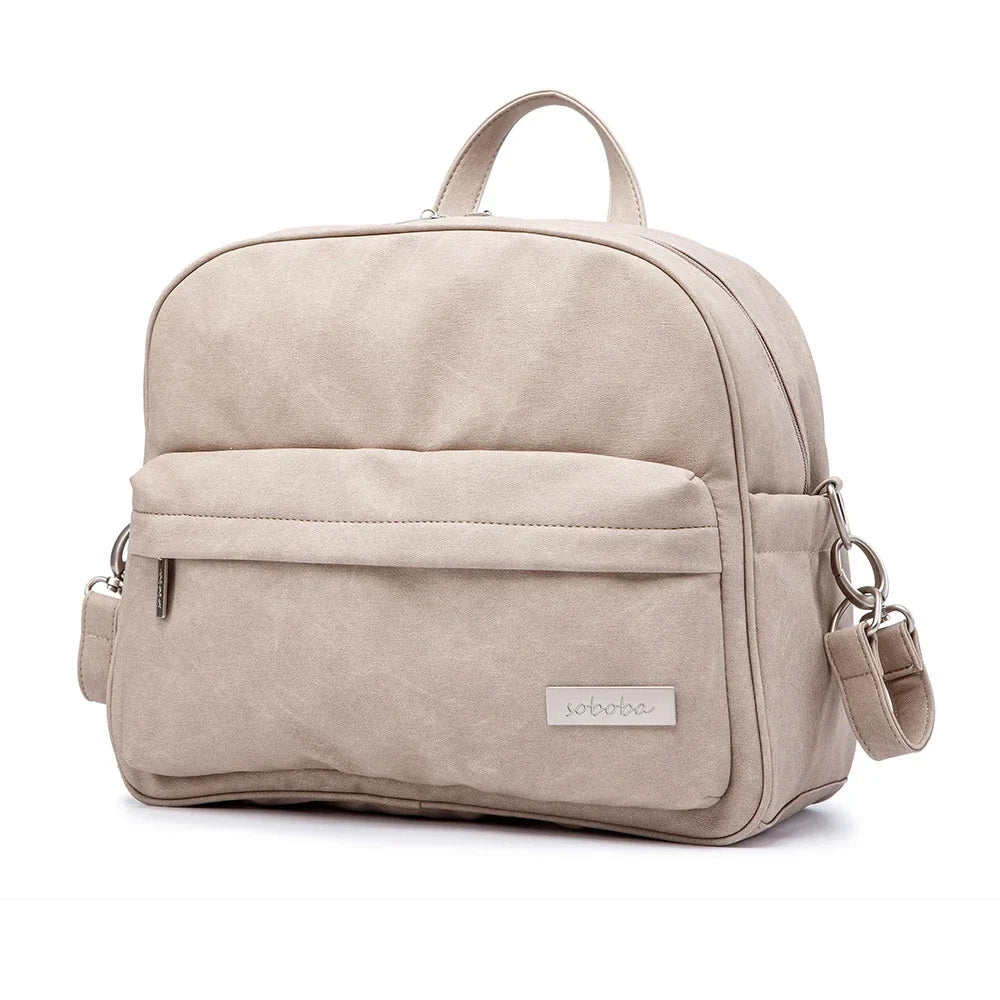 Modern diaper backpack in black PU leather with multiple compartments for stylish parents