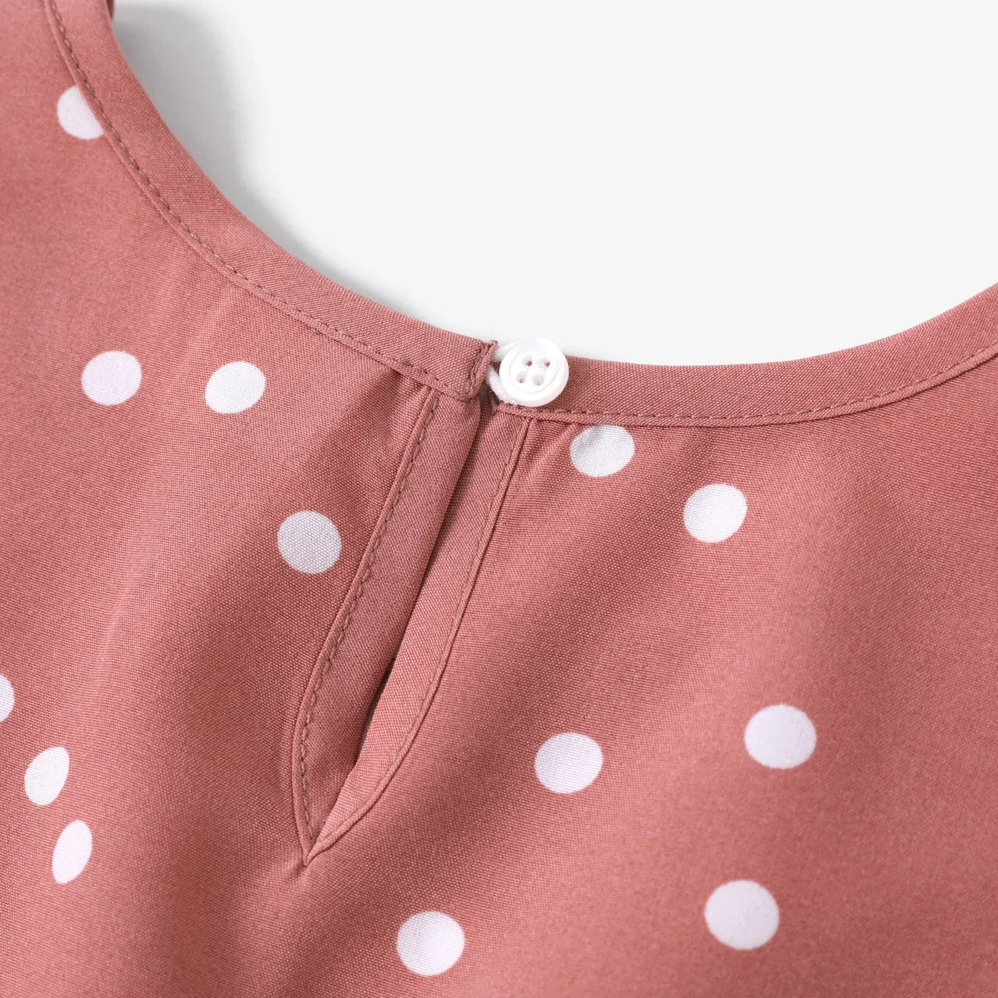 Child twirling in a delightful pink dotted cross wrap dress, showcasing its flowy design