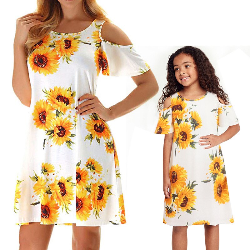 Happy family moment featuring mom and daughter in matching sunflower summer dresses.