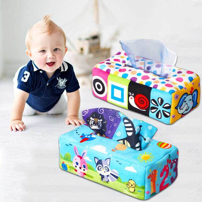 Top view of a baby's hand reaching for a silk scarf in a Montessori sensory tissue box toy