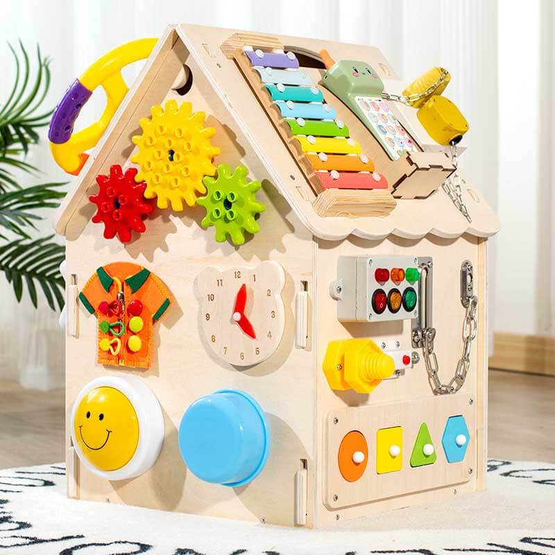 Close-up of a toddler's hand interacting with a latch on a wooden Montessori busy house toy.