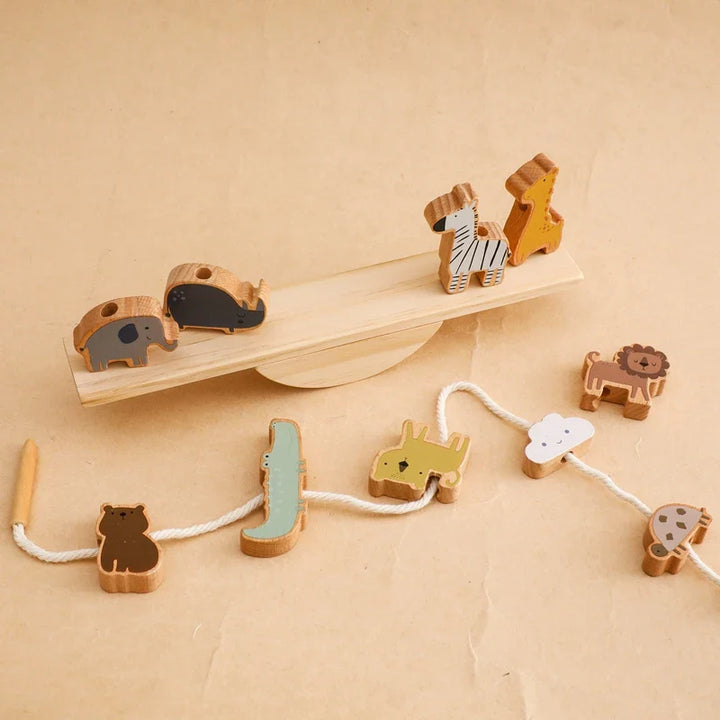 Close-up of a child's hands threading a wooden animal onto the seesaw balancing toy