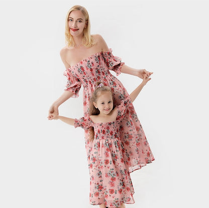 Mother and daughter in matching pink off-shoulder terylene summer dresses, smiling outdoors.