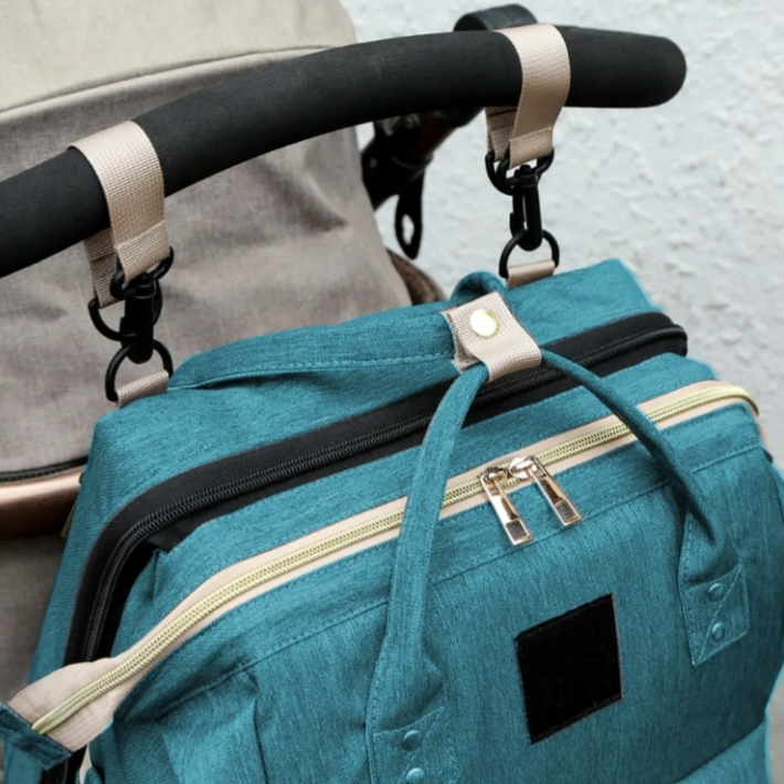 A parent's hand unzipping the diaper bag to reveal the integrated portable changing bed for quick setup