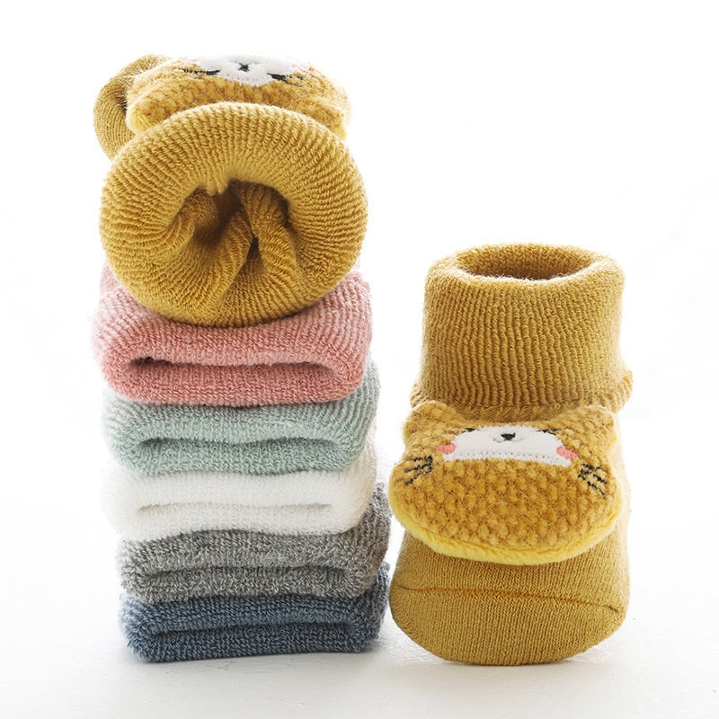Overhead view of anti-slip baby walking socks laid out, showcasing animal designs & grip soles