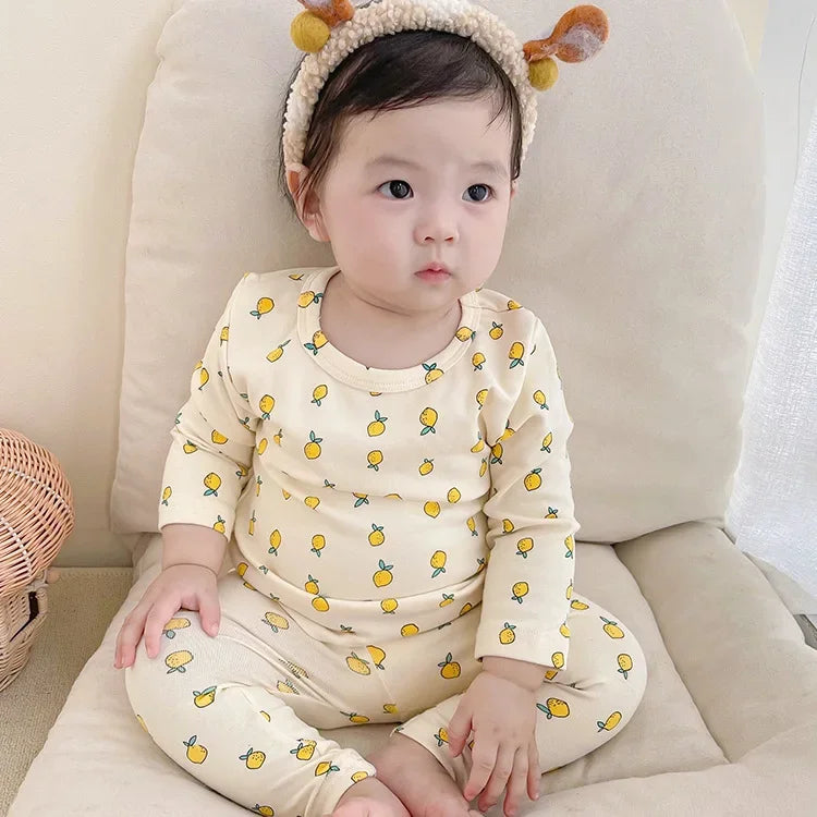 Flat lay of a baby cotton top and pant set in a neutral color, essential infant wear.