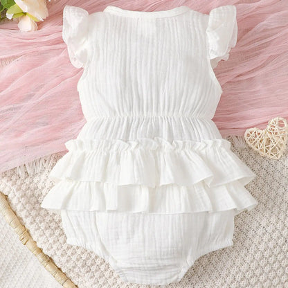 Close-up of white halter dress for newborn baby girl, showing soft cotton fabric and tie-neck detail.