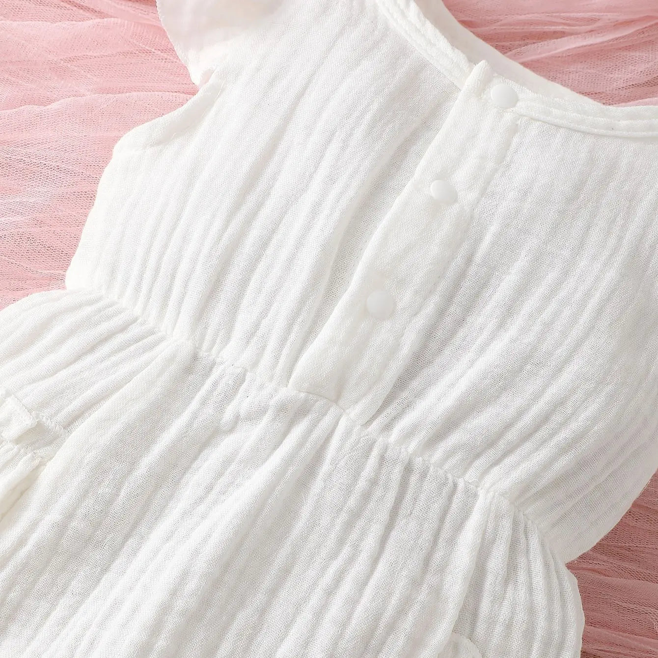 Adorable baby girl modeling a sleeveless white halter dress, ideal for summer special occasions.