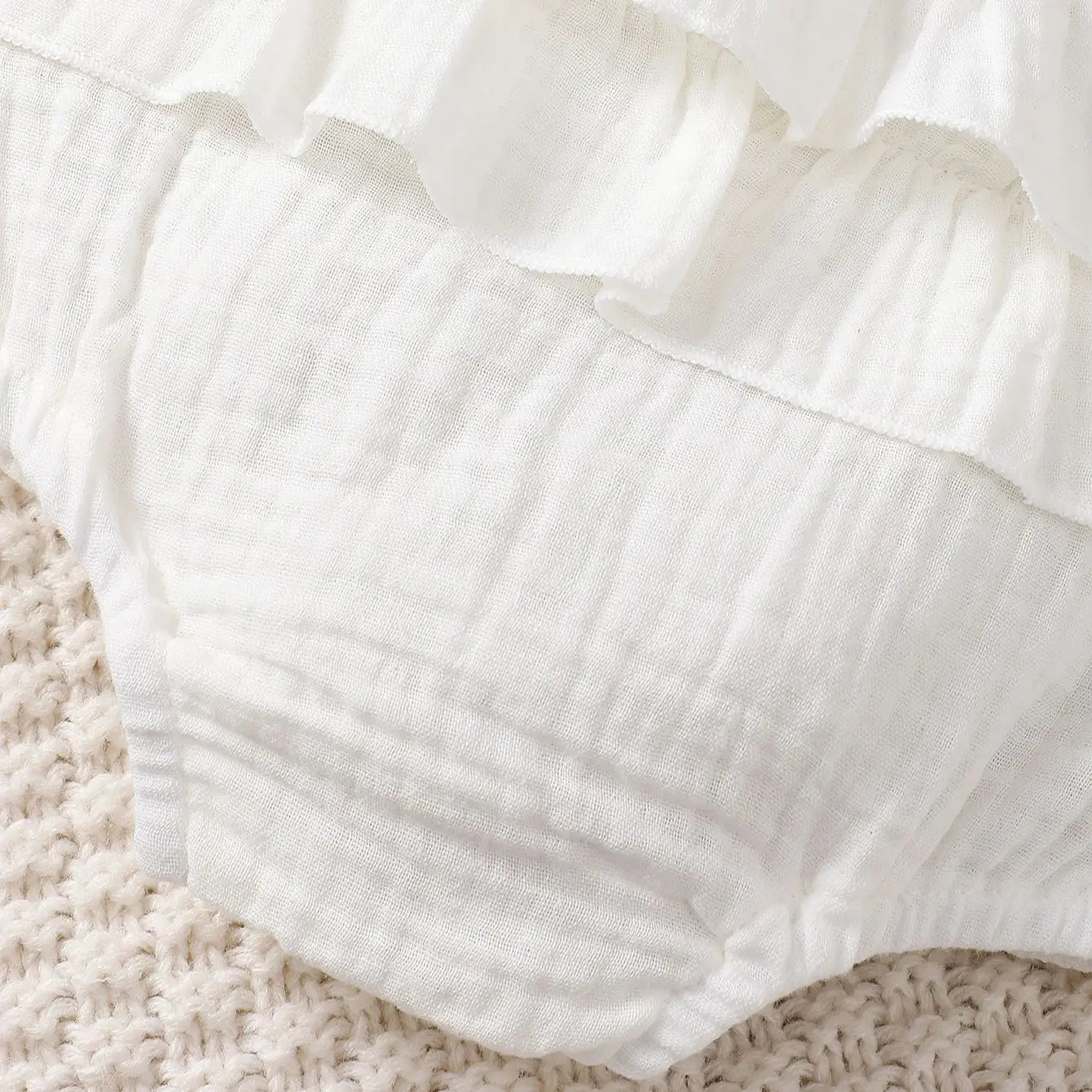 Full view of a newborn white halter dress, highlighting its breathable cotton design for warm weather.