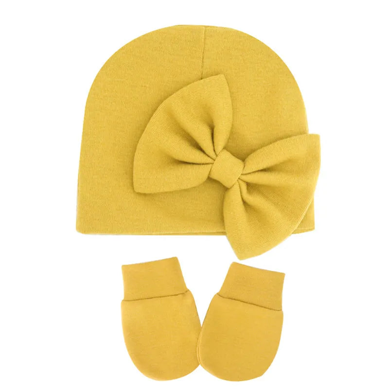 Newborn baby girl's pink cotton hat featuring a little decorative bow.