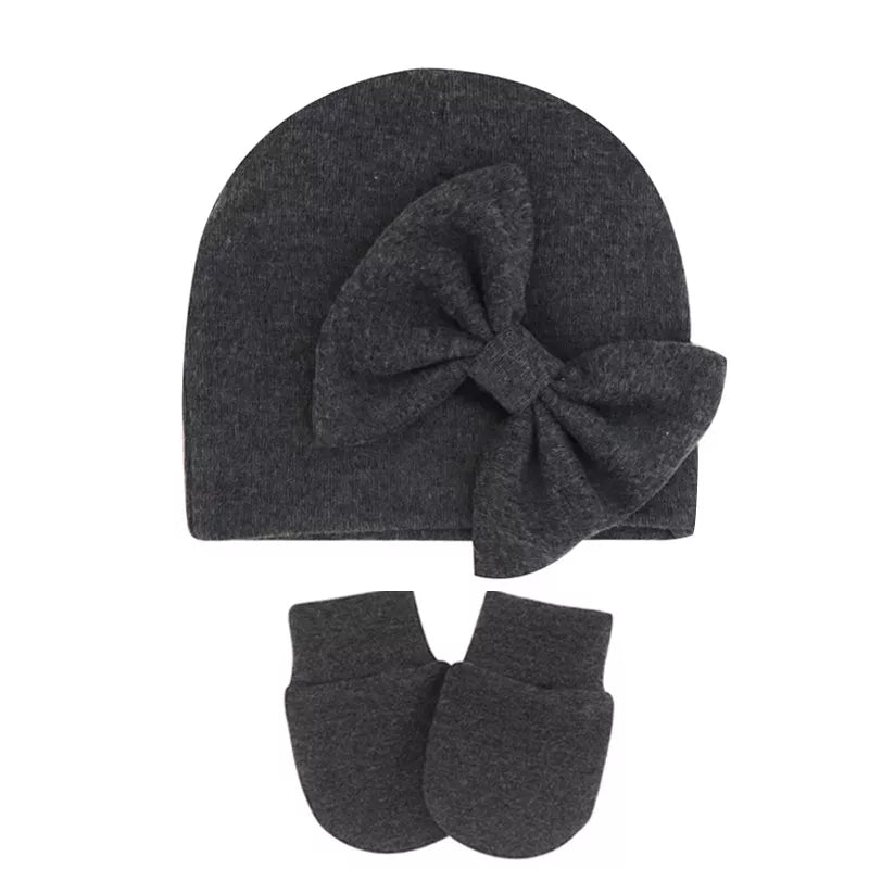 Descriptive image of a newborn baby girl's cotton hat with a simple bow.