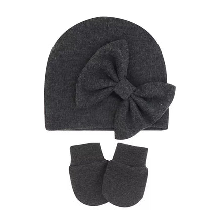 Descriptive image of a newborn baby girl's cotton hat with a simple bow.