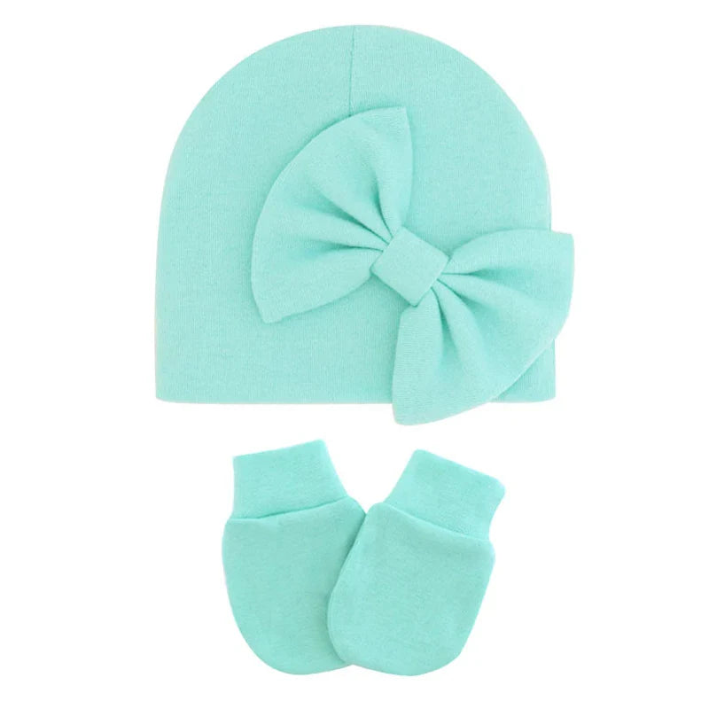 Newborn girl's cotton hat and mittens set, ideal for keeping baby cozy.