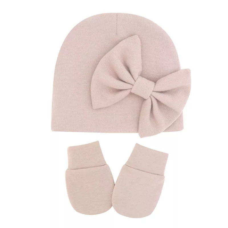 Light pink cotton newborn hat and mitten set on a white background.