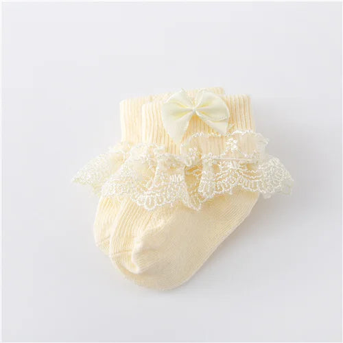 Baby girl's white lace socks with a princess bow on a clean background, infant fashion