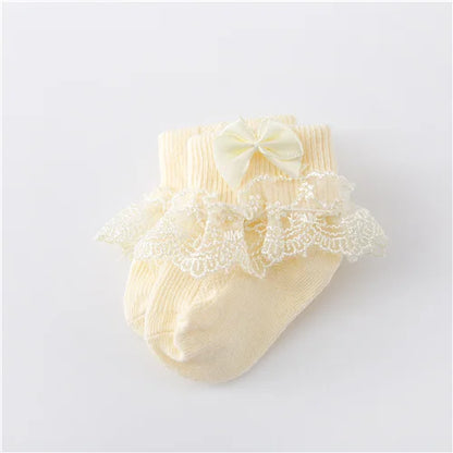 Baby girl's white lace socks with a princess bow on a clean background, infant fashion