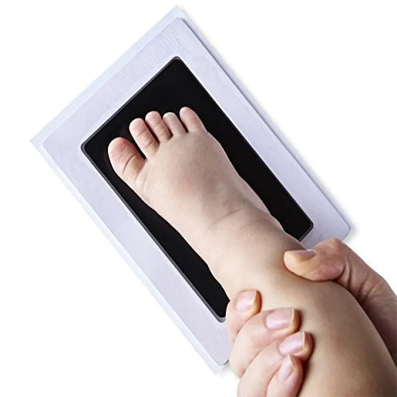 Close-up of a baby's delicate hand being pressed onto the non-toxic ink pad of a footprint kit.