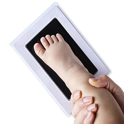 Close-up of a baby's delicate hand being pressed onto the non-toxic ink pad of a footprint kit.
