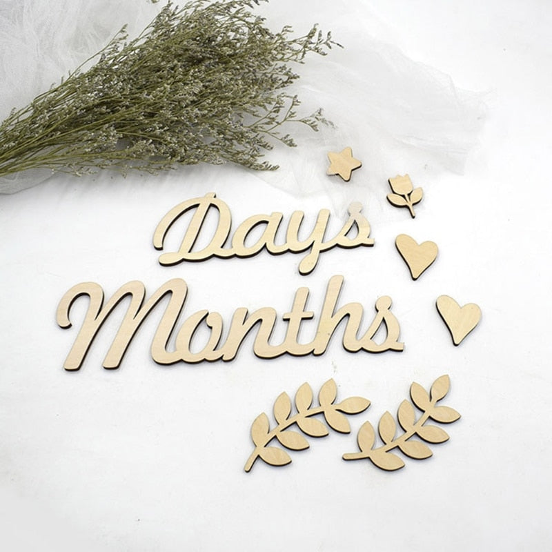 Close-up of a baby's hand holding a wooden milestone card, perfect for newborn photography.