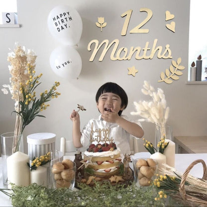 Arrangement of newborn photography props including wooden milestone cards on a soft blanket.