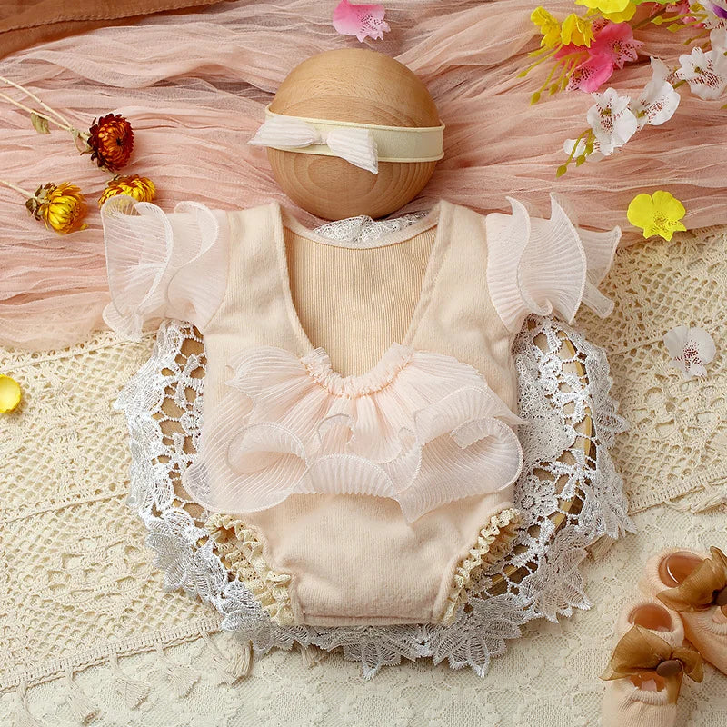 Top-down view of a baby in a lavender lace romper and matching bow headband for photos
