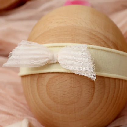Close photo of the bow headband from the newborn girl lace romper set, pink, soft fabric