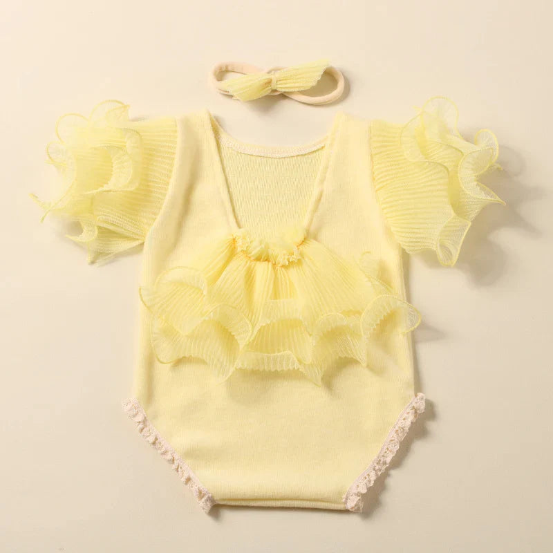 Newborn girl dressed in a delicate lace romper and bow headband, perfect for cherishable photos