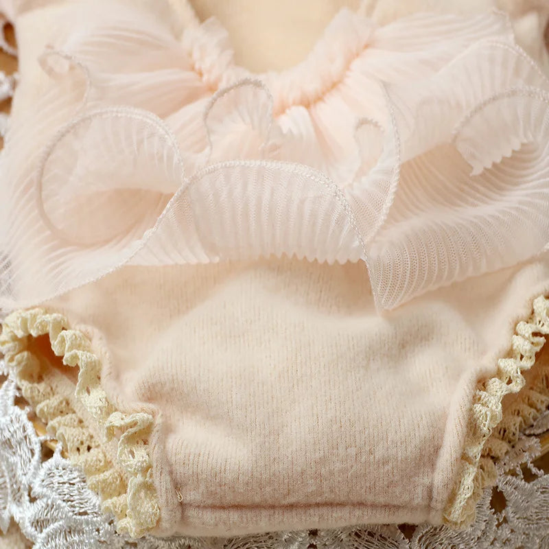 Close-up of a newborn girl wearing a pink lace romper, showcasing intricate lace details