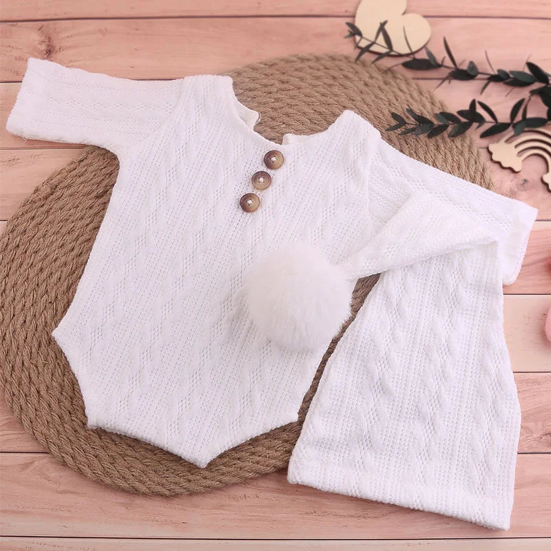 Close-up of a knitted newborn jumpsuit texture with a pompom hat detail