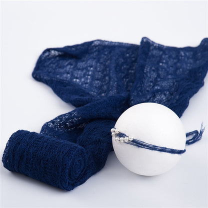 Close-up of a newborn wrapped snugly in a cream mohair swaddle with a matching head wrap, photography prop.