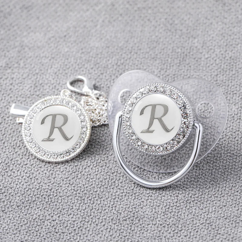 Close-up of silver bling newborn pacifier and clip, high-quality baby essential