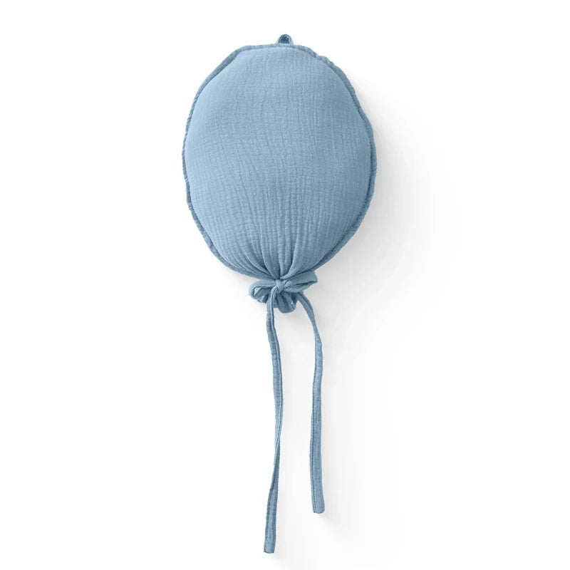 Balloon shaped baby pillow on a shelf with other Nordic decor items in a children's room