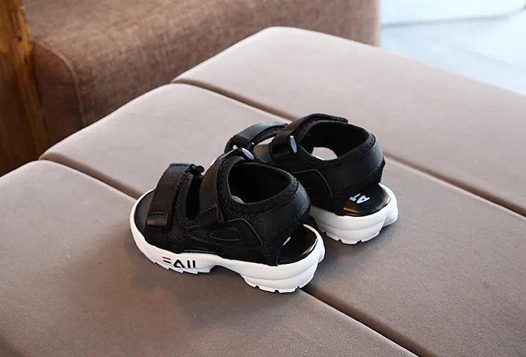 Blue slip-on sport sandals for children, displayed on a wooden deck, ready for summer outings.