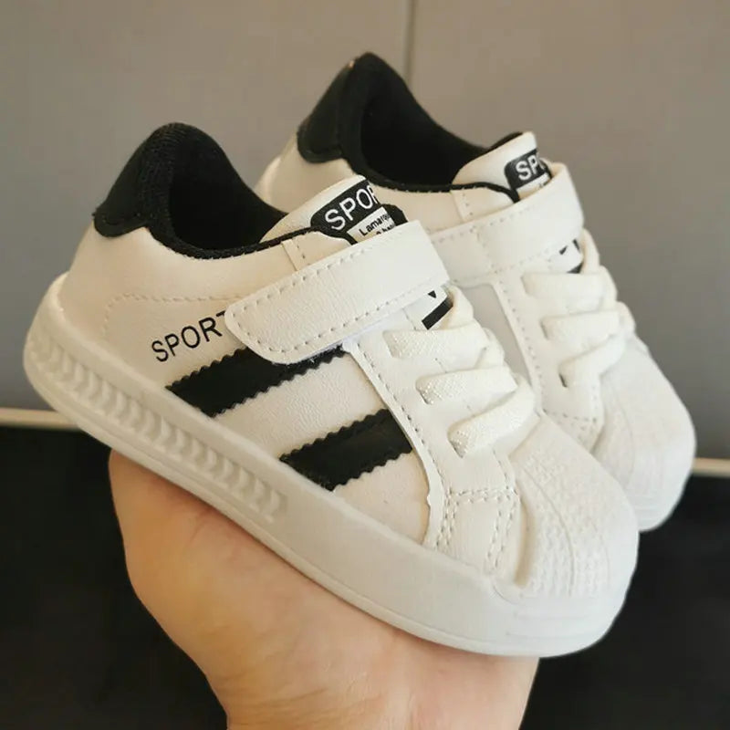Smiling toddler wearing white anti-slip casual sneakers, running happily on a playground, showcasing comfort and secure fit.